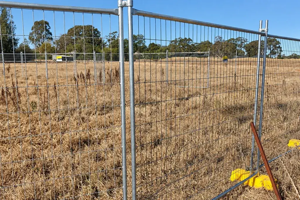 Temporary mesh fence standing on dry grassy ground