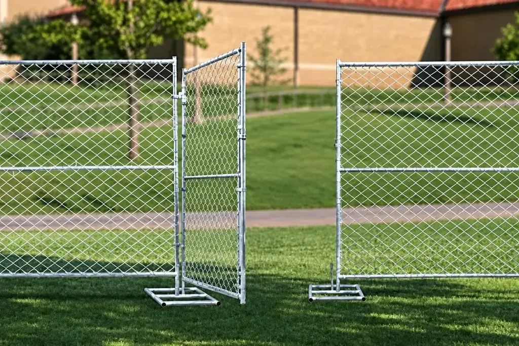 Open temporary chain link gate between freestanding fence panels