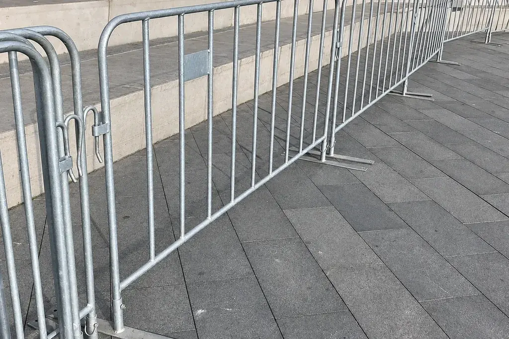 Long line of metal crowd barriers deployed along a paved route