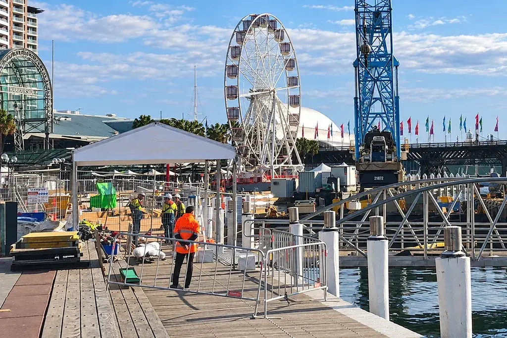 Metal crowd barriers around a waterside event build area
