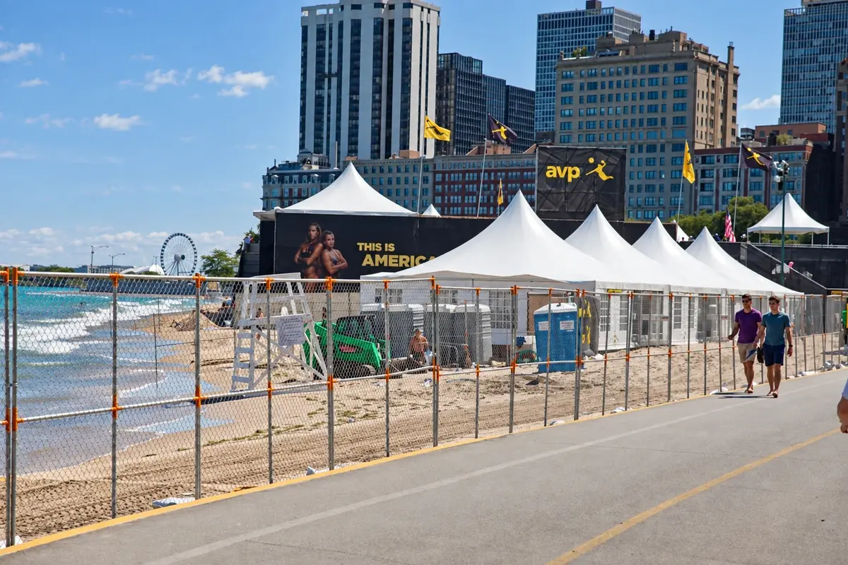 Temporary chain link fencing beside event tents and a public path