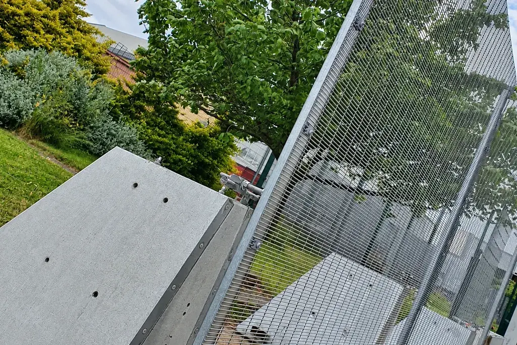 Dense mesh rapid deployment fence panel beside a concrete support block