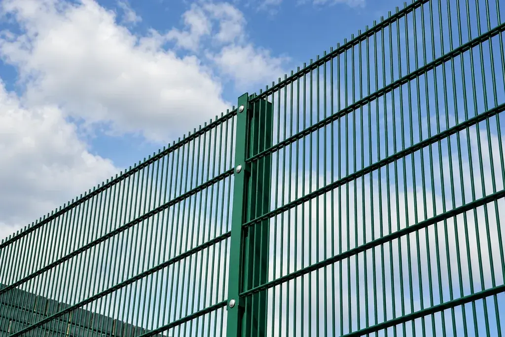 Green double wire mesh fence installed outdoors with posts