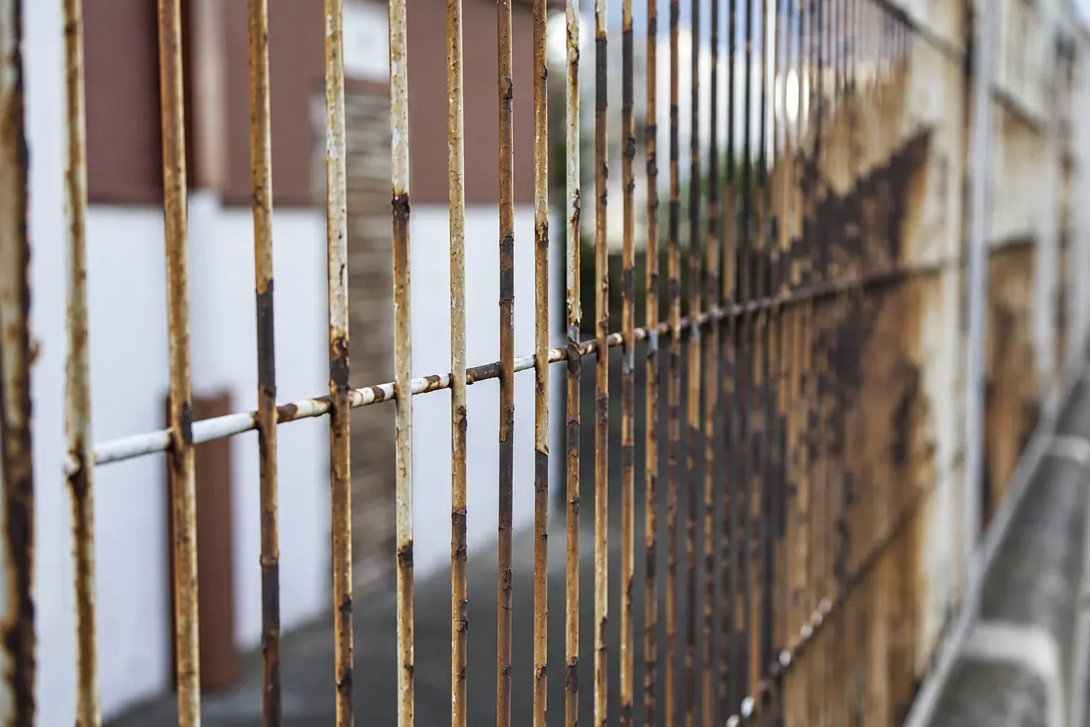 Close view of rust on a steel mesh fence beside a building