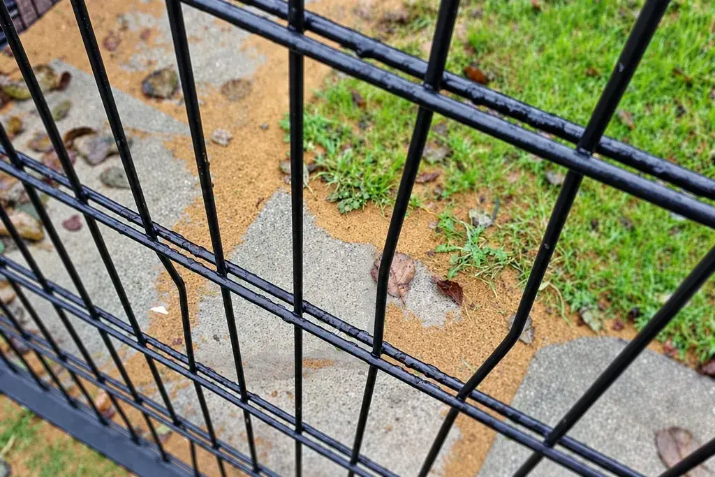 Close view of a damaged black coated wire mesh panel