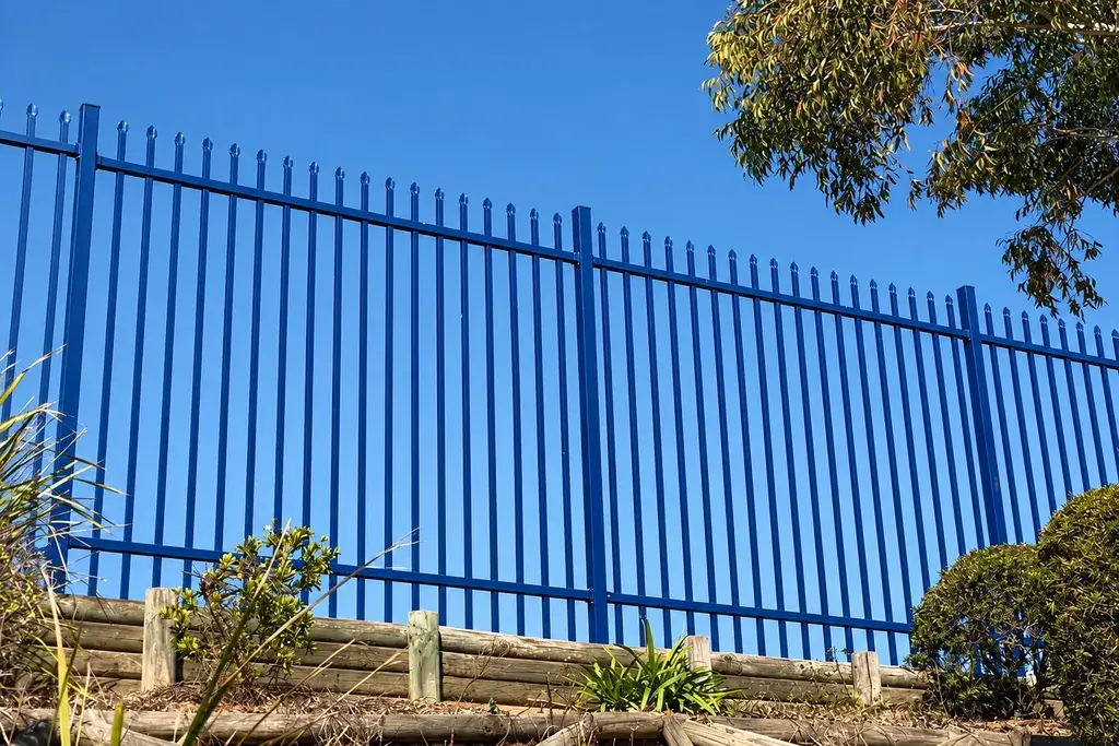 Blue coated metal fence installed along a landscaped boundary