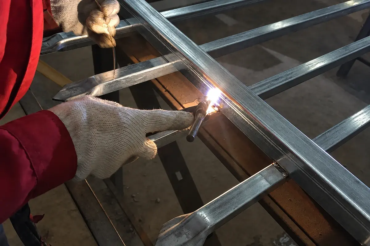 Worker welding a steel fence frame in a workshop