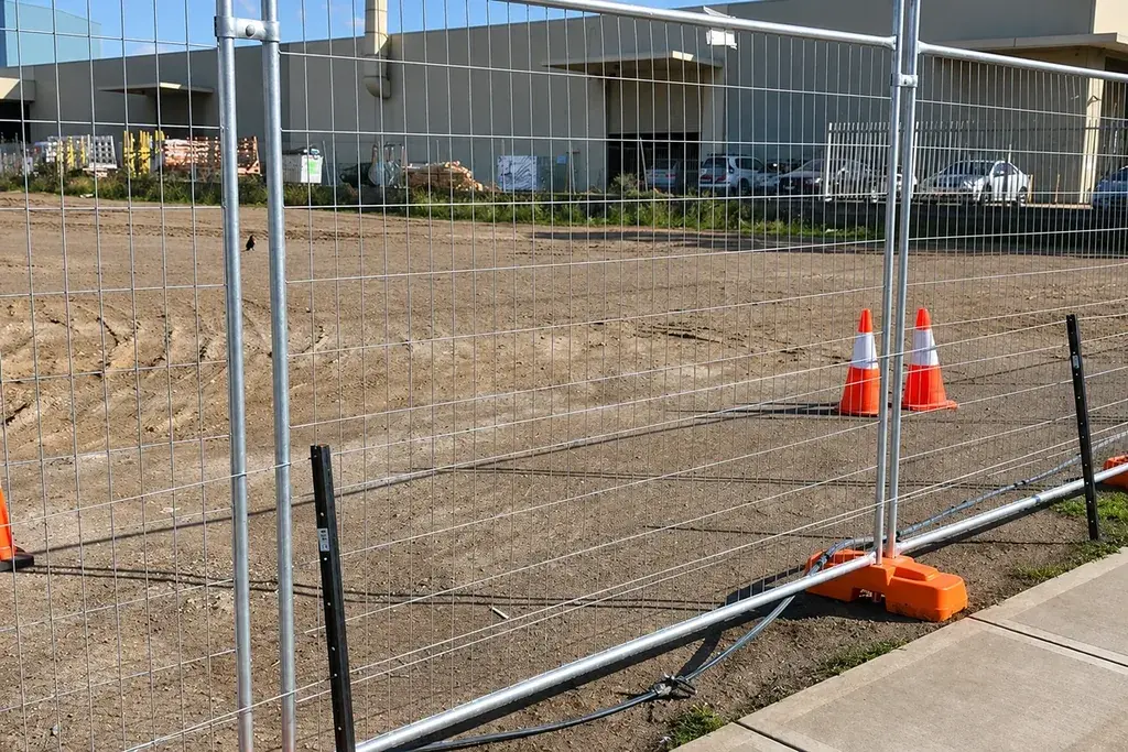 Temporary welded mesh fence panels with orange feet at an industrial site