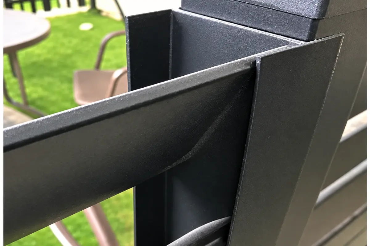 Aluminium slat fitted into a channel at a dark fence post