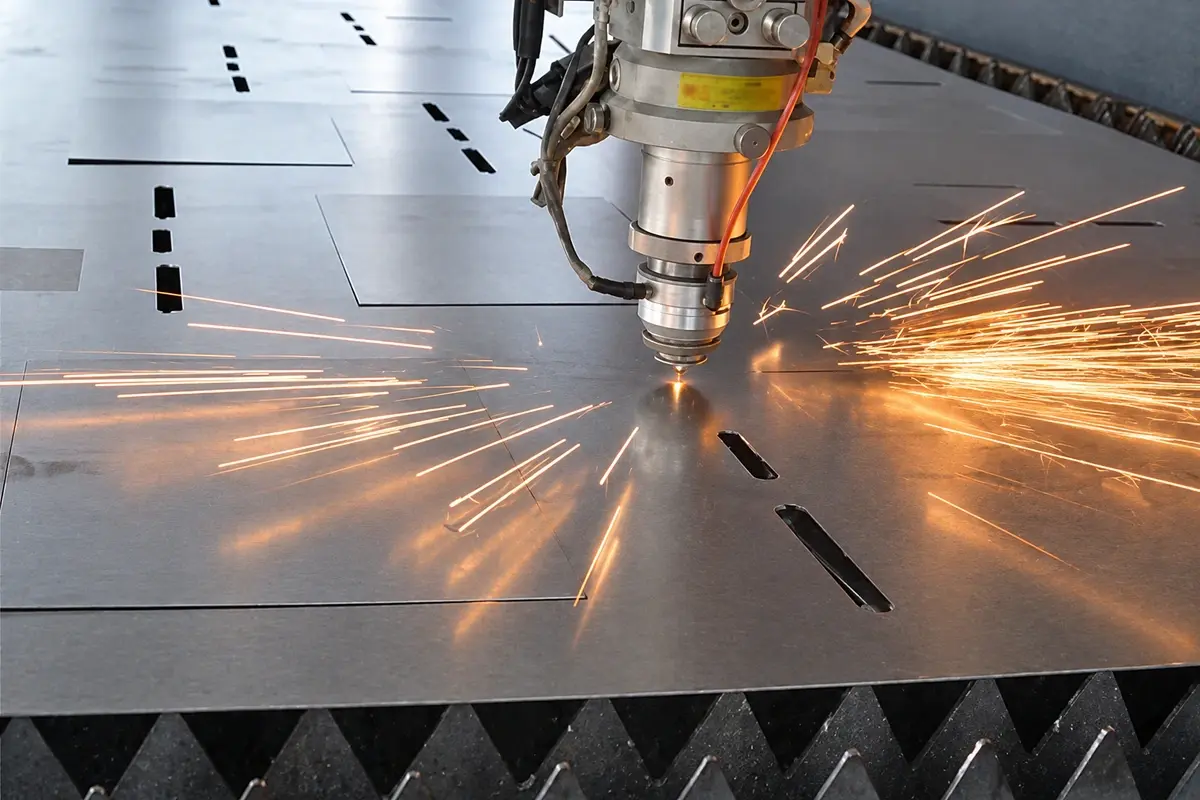 Laser cutting head working on a metal sheet in a workshop