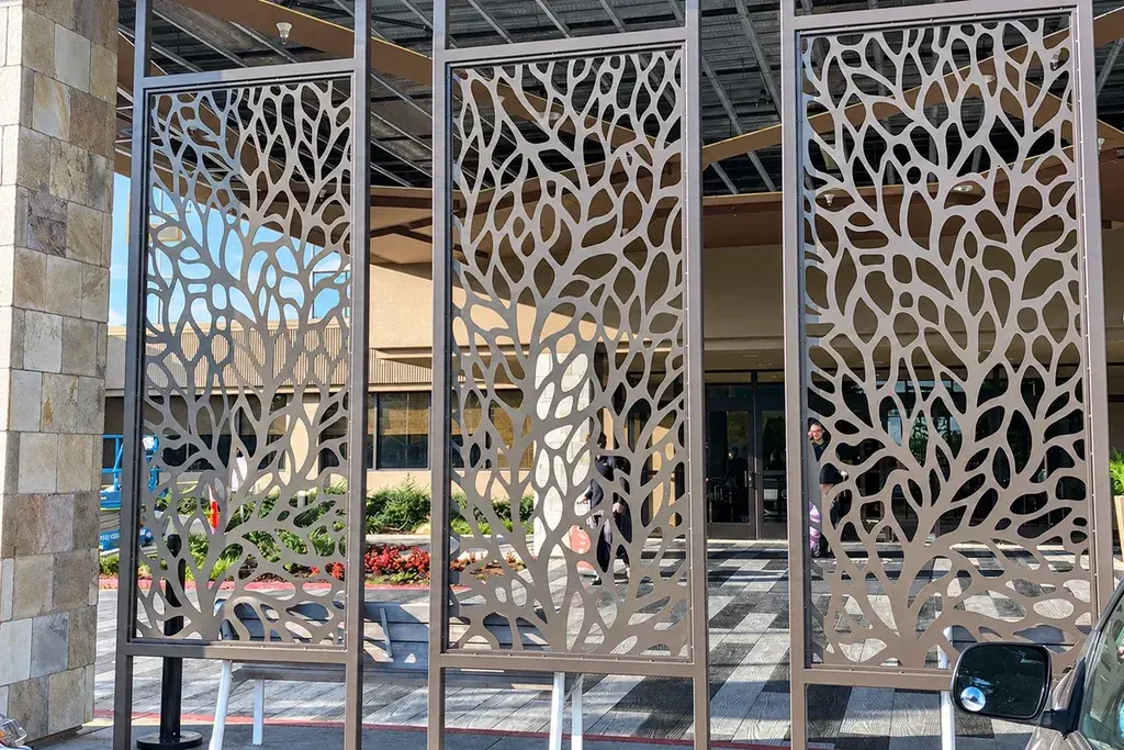 Three installed metal screen panels with repeating branching cut-out patterns