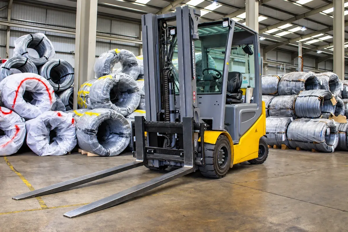 Forklift beside packed fence rolls in a warehouse