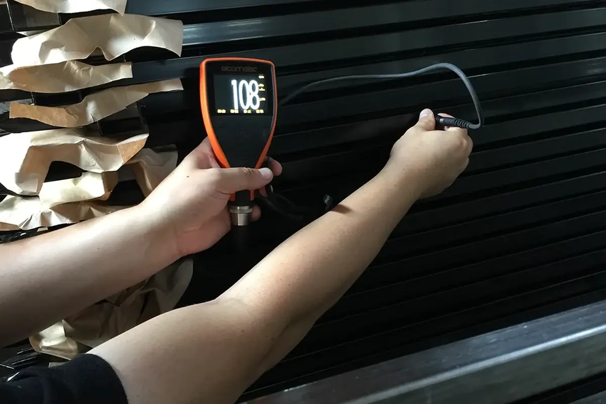 Handheld temperature instrument aimed at a coated metal fence panel