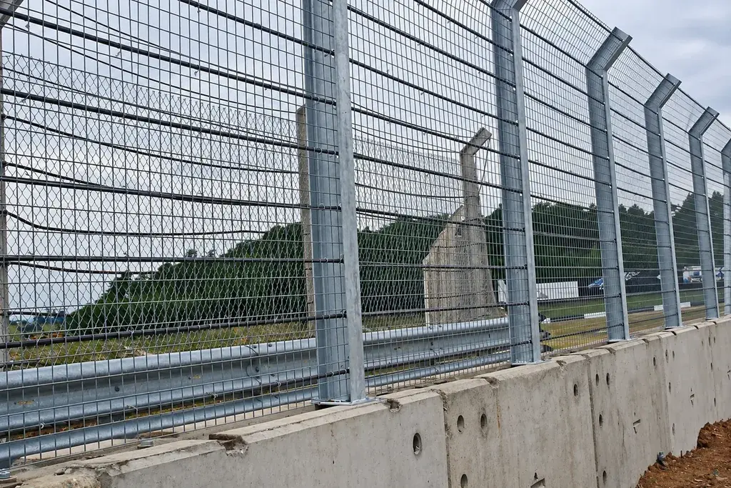 Metal mesh fence fixed along a concrete retaining wall