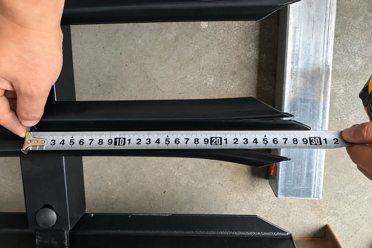 Hands measuring a steel palisade component against a rail