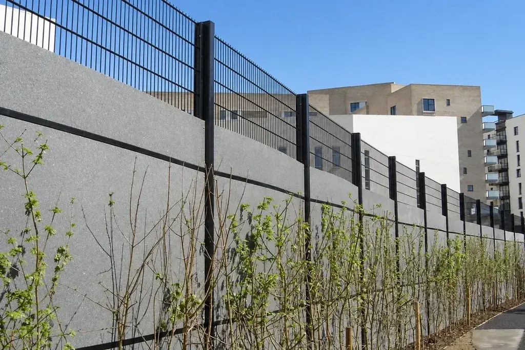 Metal fence beside a high wall at an urban site