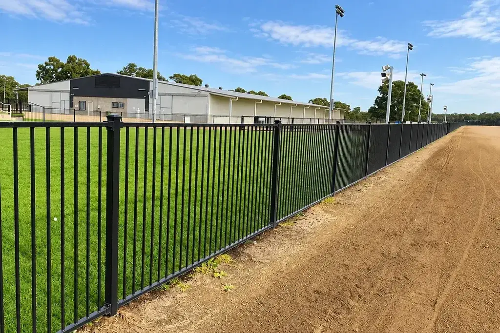 Long installed black steel fence with repeated posts beside a path
