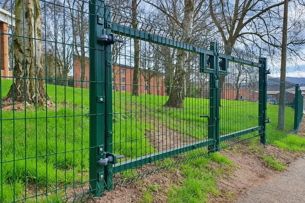 Installed green profiled mesh fence with visible post clamps