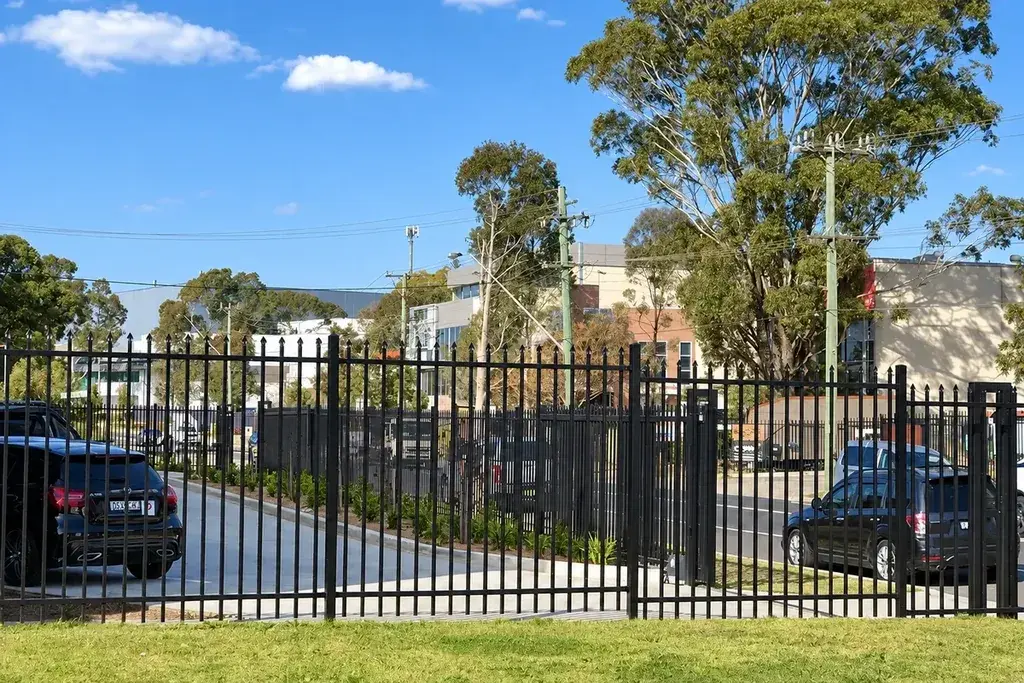 Black steel fence and vehicle gate along a roadside property