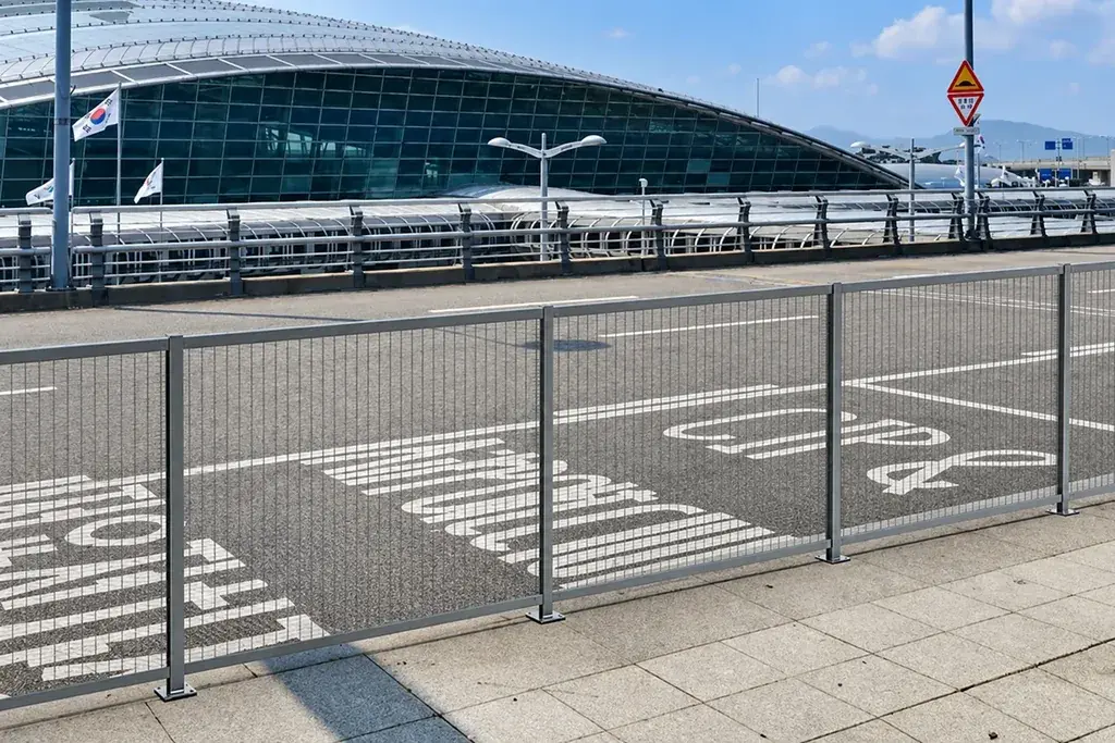 Installed mesh fence panels and posts beside a paved site