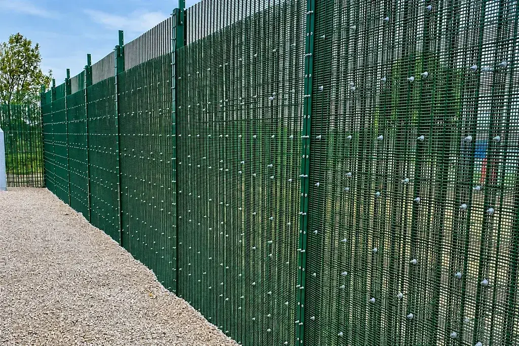 Green security mesh fence panels and posts along a boundary