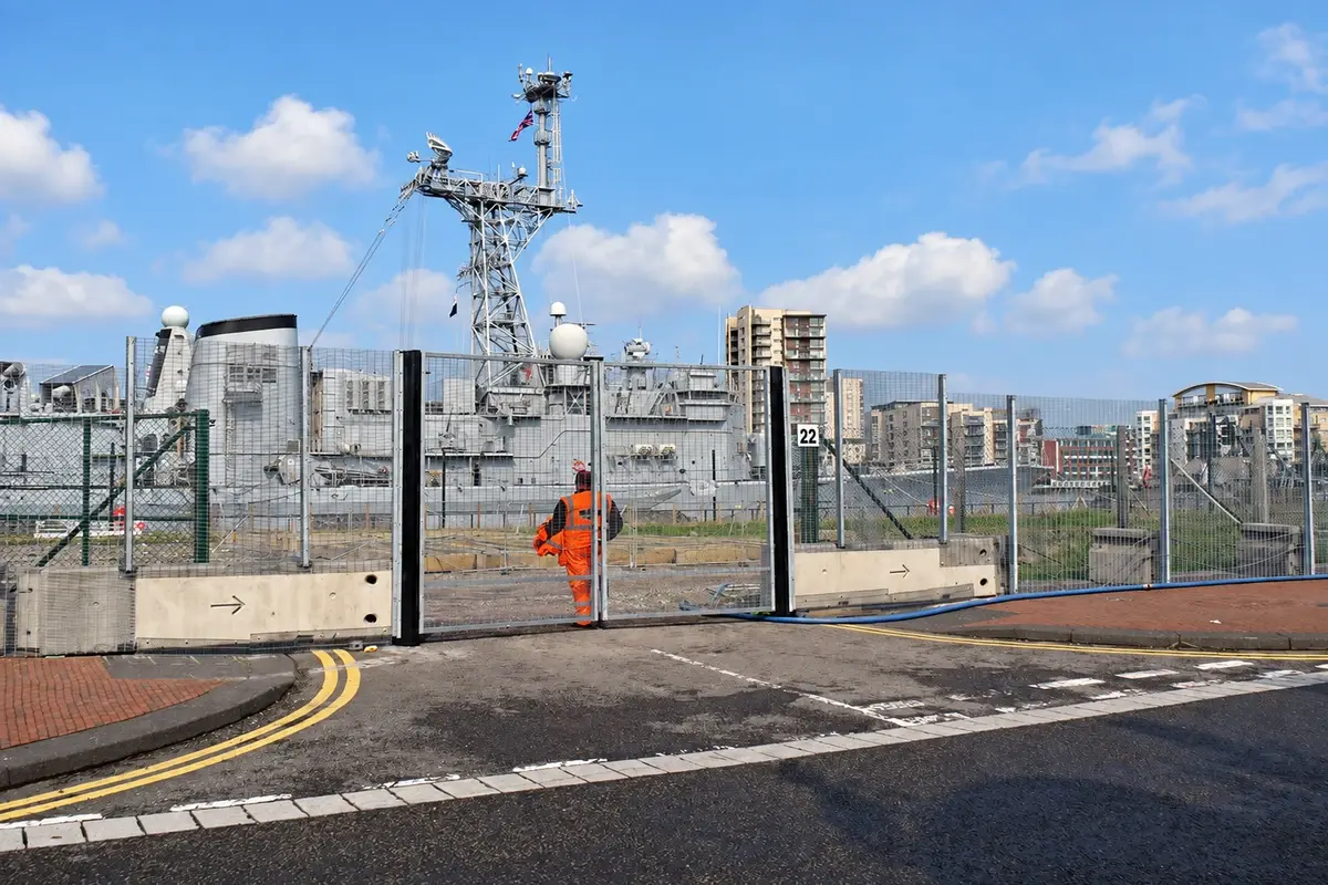 Security mesh fence at a port facility beside industrial equipment