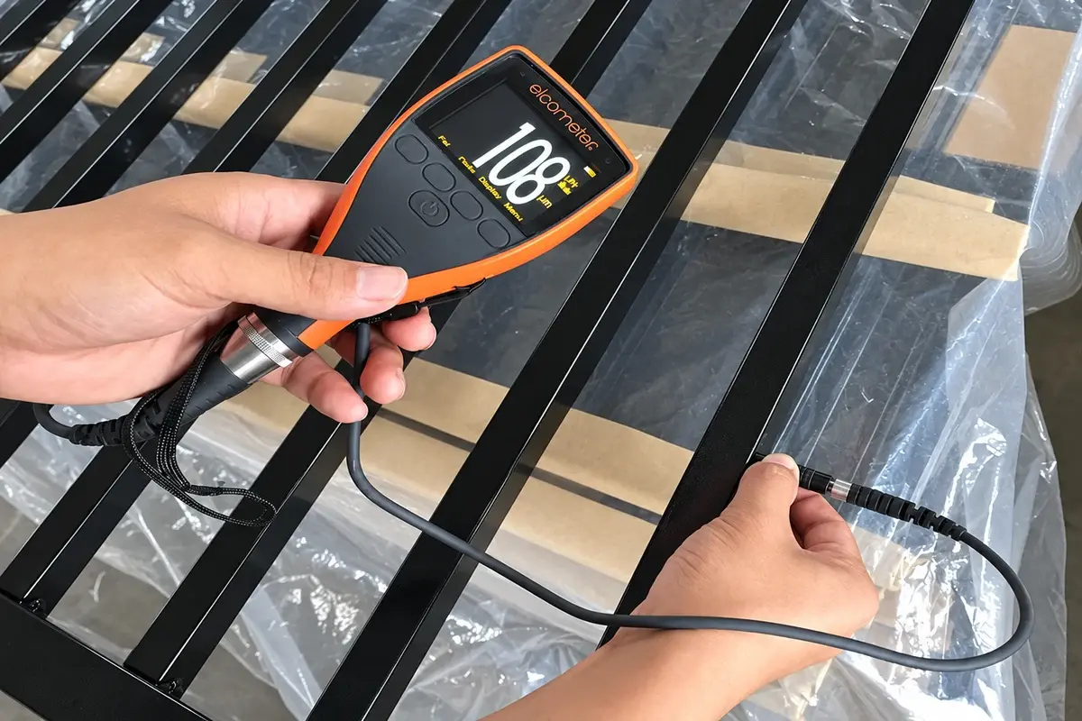 Handheld coating gauge checking a black steel gate component