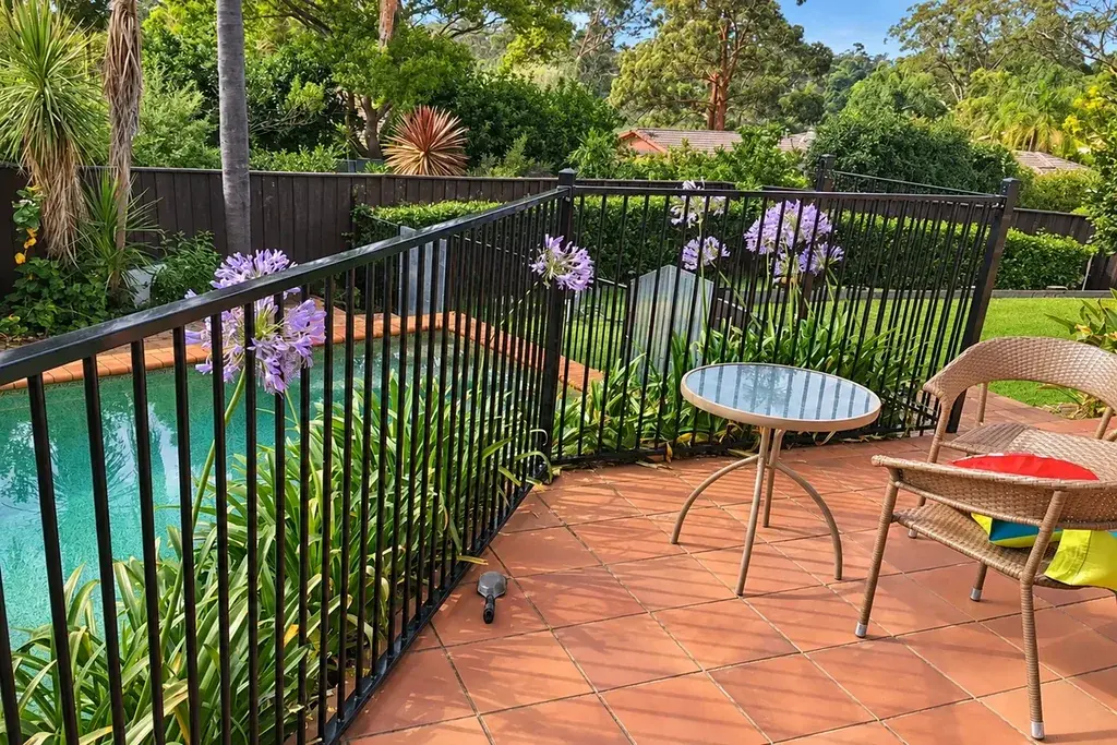 Black pool fence beside a raised deck with a table and chairs