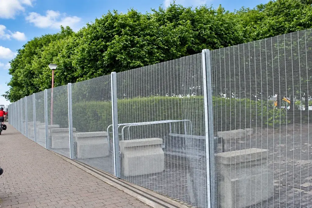 Tall mesh security fence with concrete support units along its base