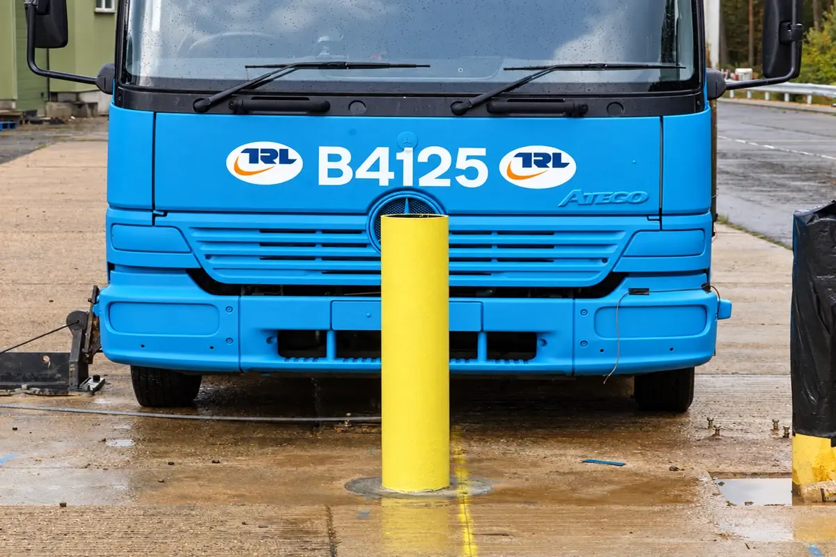 Blue test vehicle facing a yellow security bollard