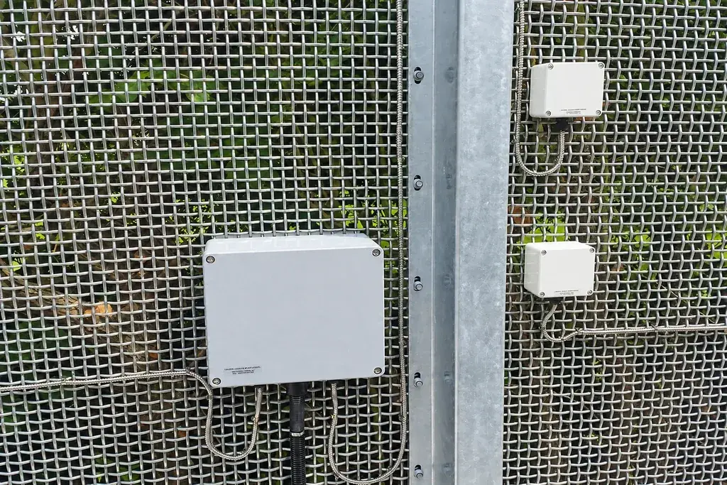 Small detection devices mounted on a metal mesh fence
