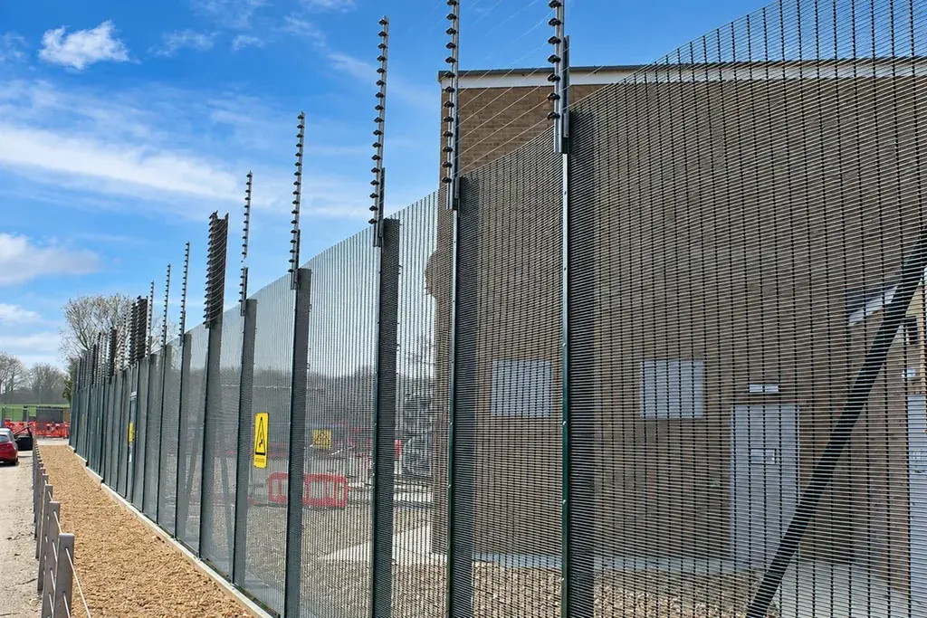 Tall security mesh fence beside an industrial building