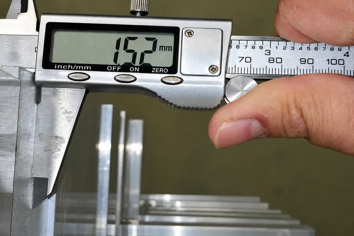 Digital caliper measuring a metal component in a workshop