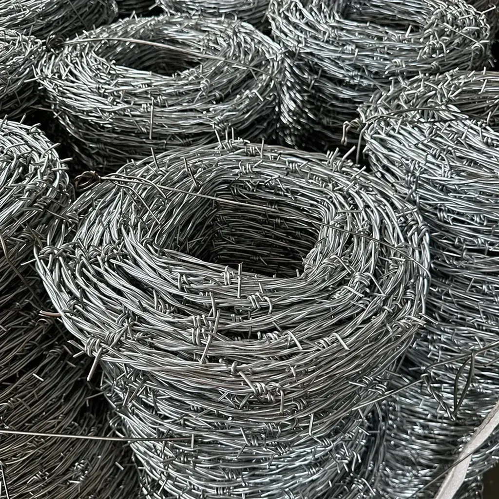Stacked coils of galvanised barbed wire with visible barbs