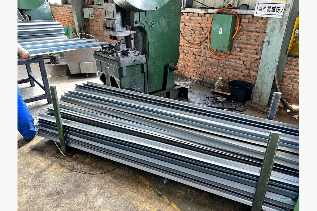 Uncoated Y-profile steel posts stacked beside cutting equipment