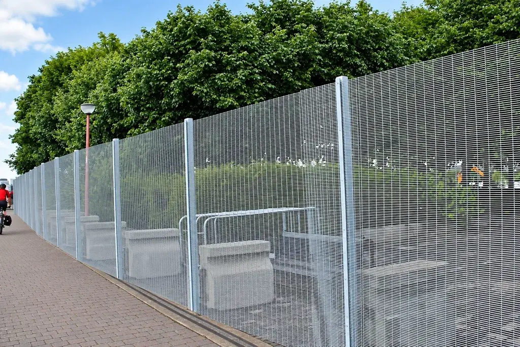 Mesh fence line with separate concrete vehicle barrier foundations