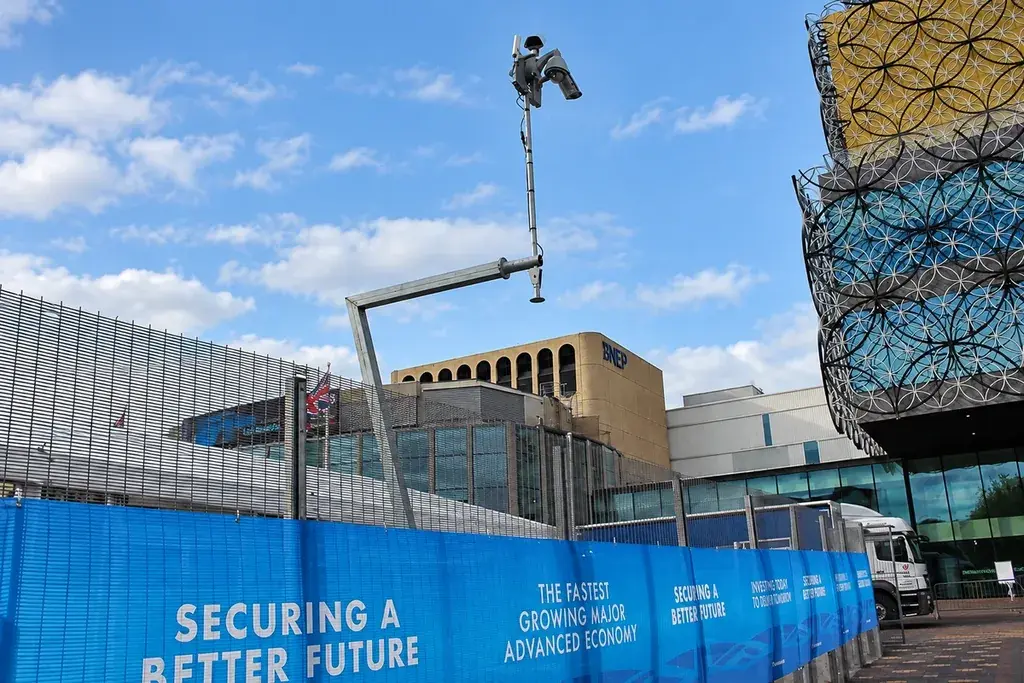 Separate steel equipment support positioned beside a secure perimeter fence