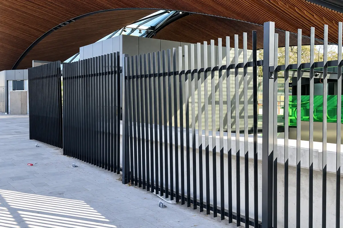Vertical metal privacy slats installed beside a vehicle access gate