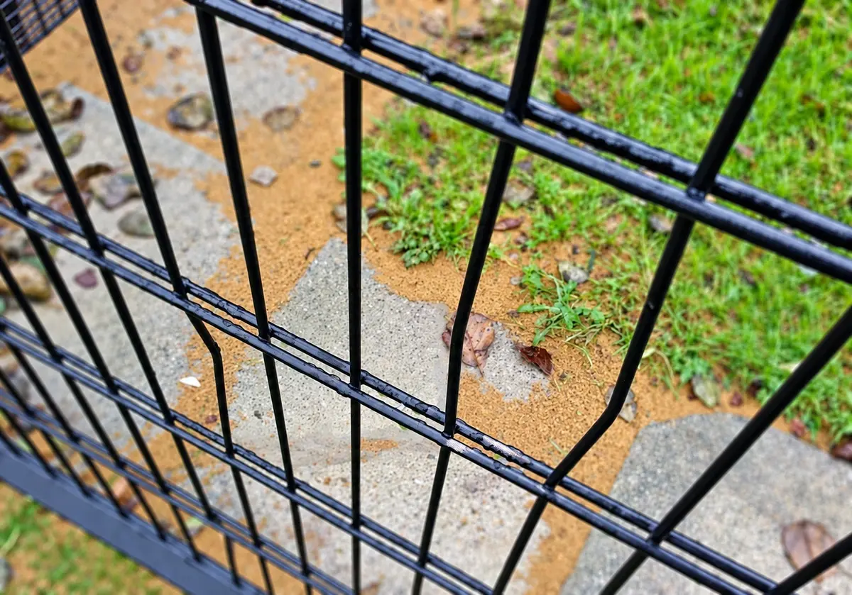 Bent wire detail on a black mesh fence panel