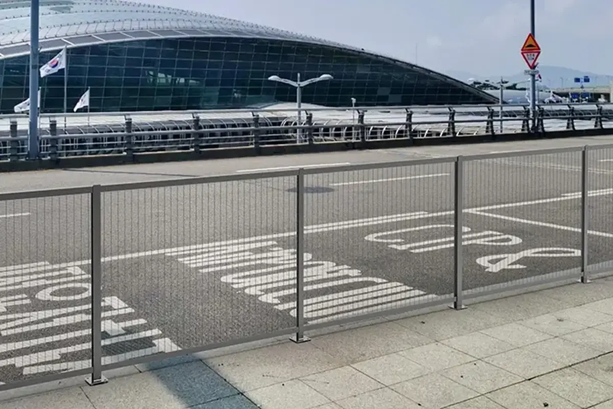 Installed mesh fence panels and posts along a roadside