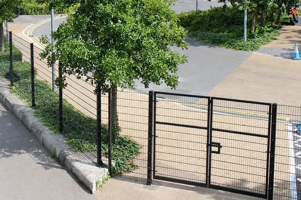 Mesh vehicle gate meeting its adjacent fence line and posts