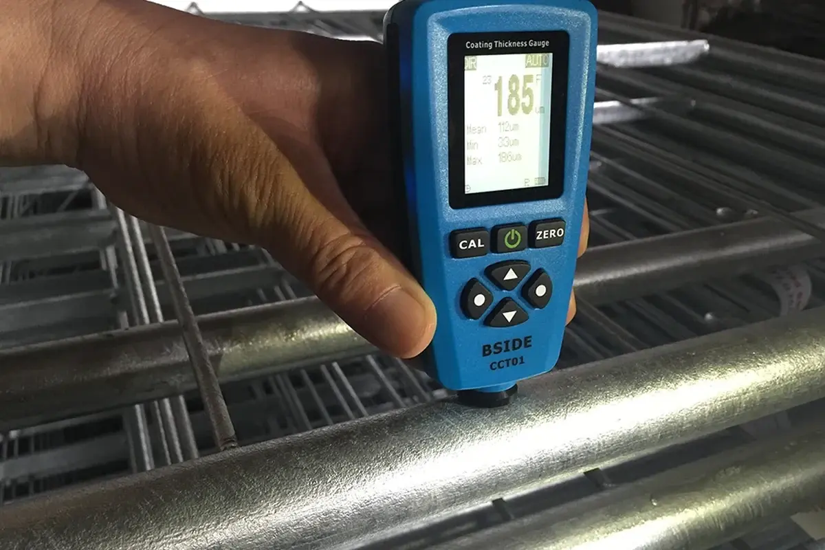 Coating thickness gauge held against a metal fence component
