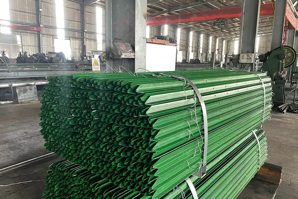 Strapped bundles of green steel fence posts in a warehouse