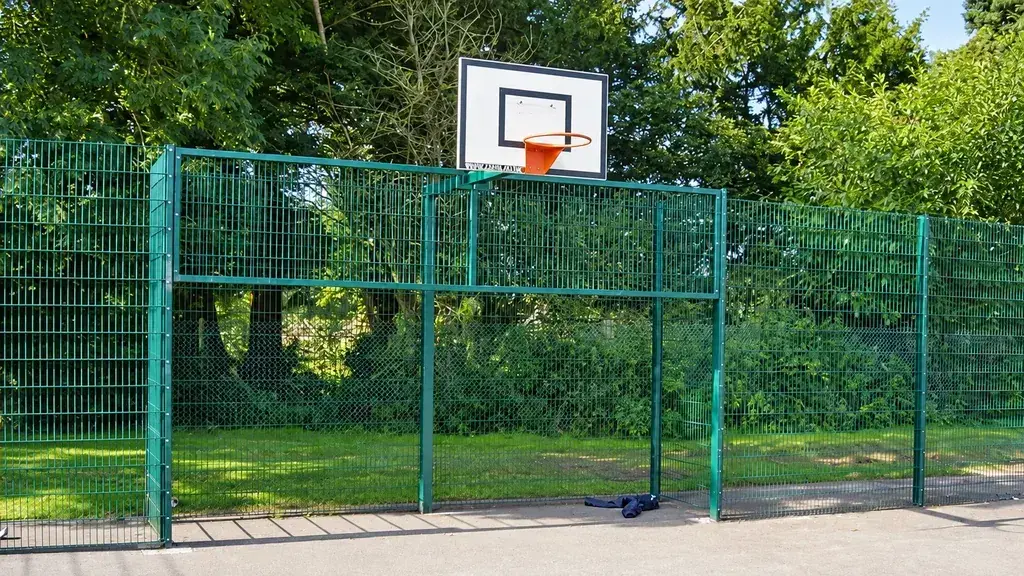 Green mesh fencing around a school basketball area
