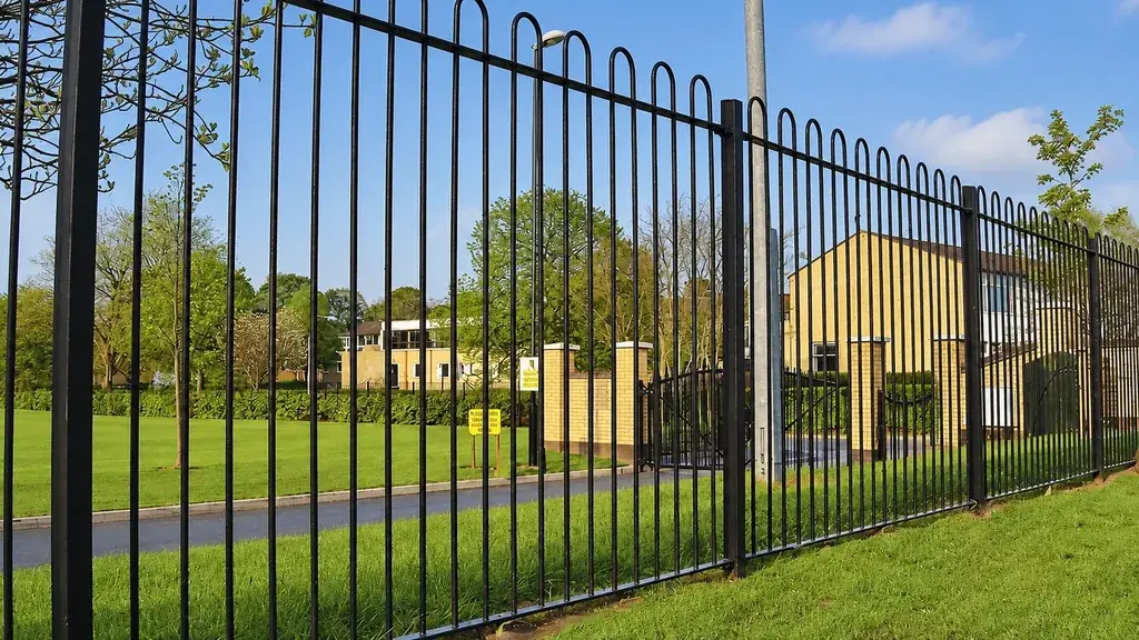 Black bow top boundary railings beside grass and trees