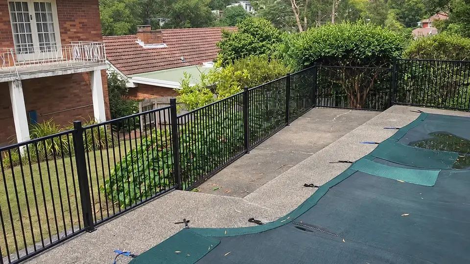 Black flat top fence beside a residential path