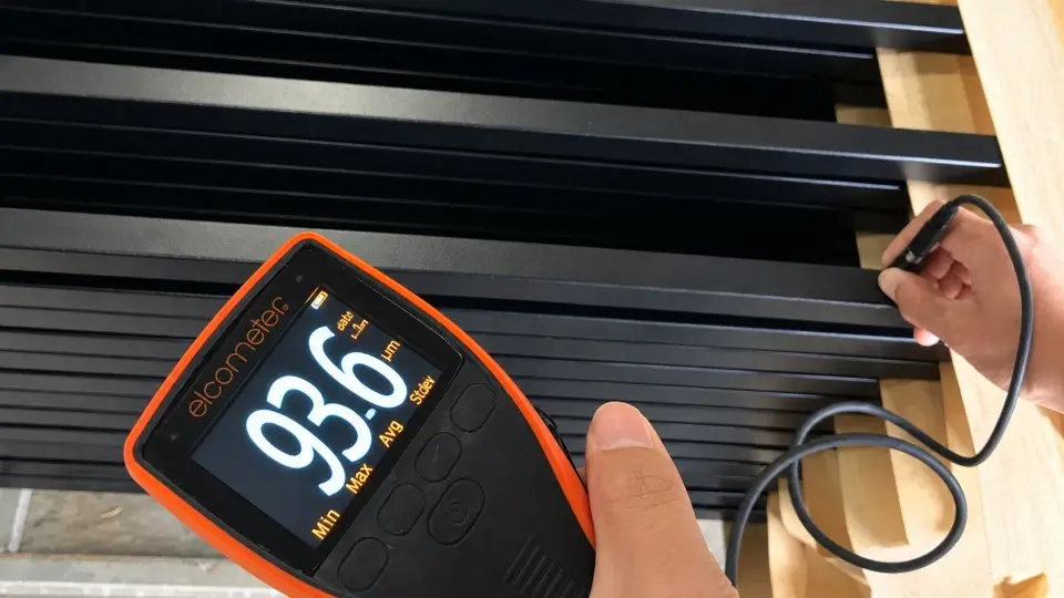Coating thickness gauge checking a black metal railing