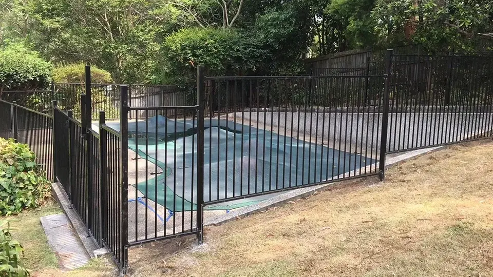 Black metal safety fence around a swimming pool