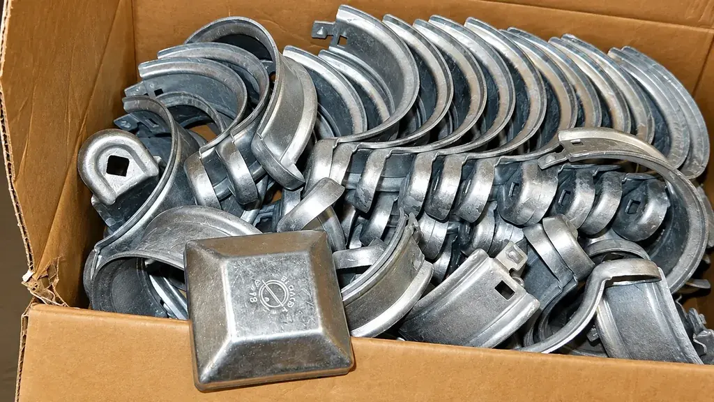 Box containing mixed metal fence brackets and caps