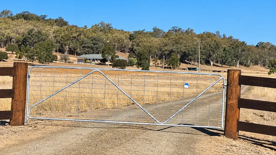 Braced mesh farm gate installed between timber posts